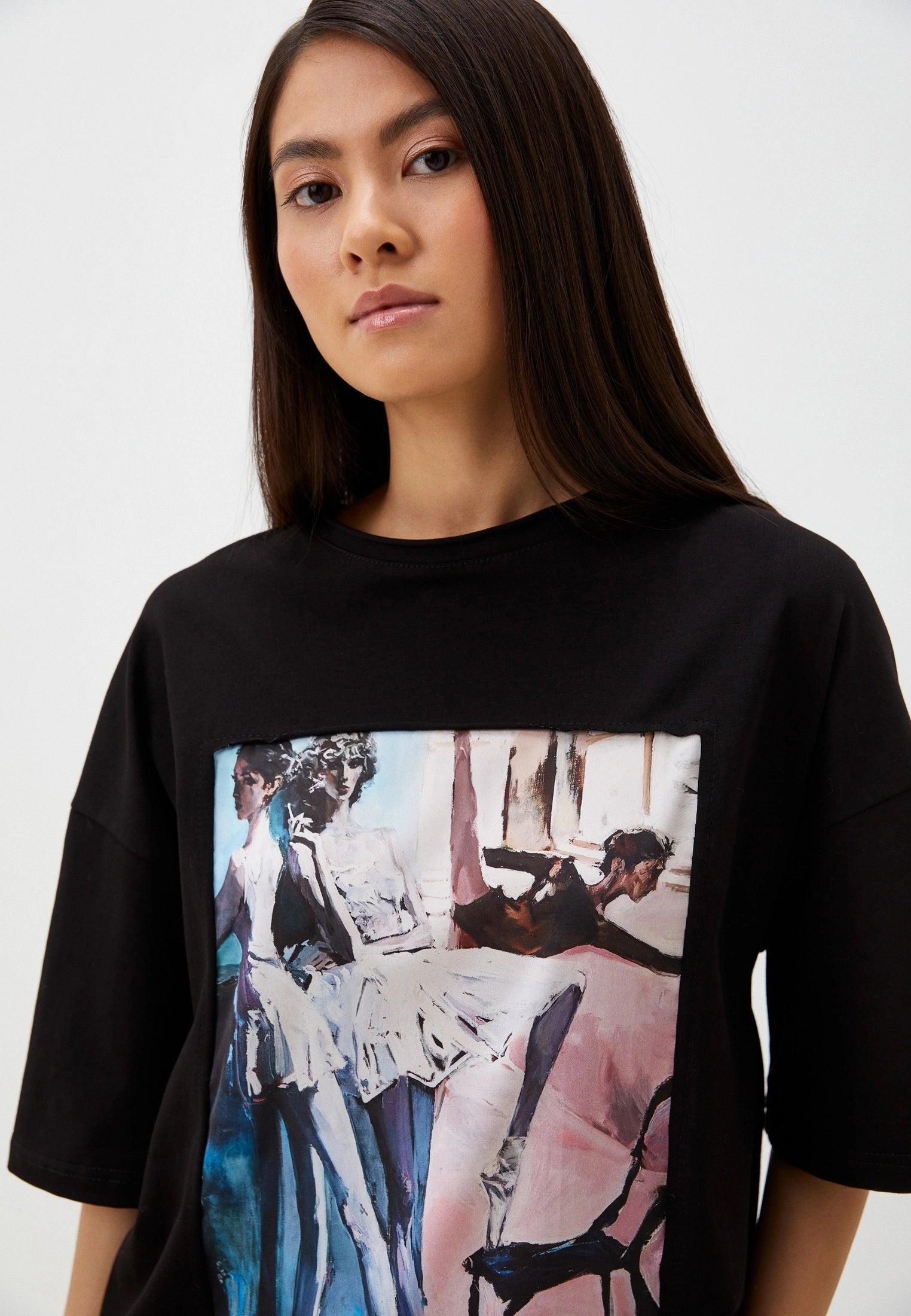 Person wearing a black t-shirt with artistic ballet print on a plain background