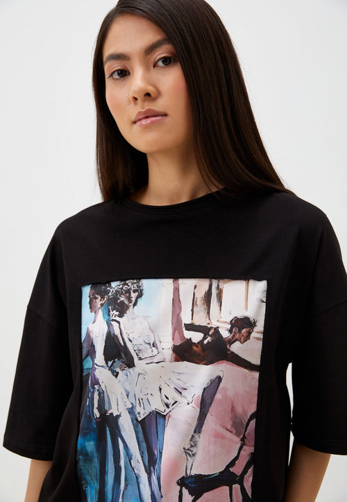 Person wearing a black t-shirt with artistic ballet print on a plain background