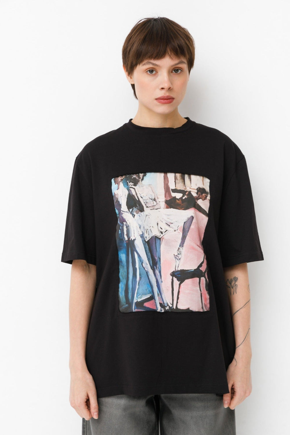 Person wearing a black t-shirt with a colorful ballet design on a white background