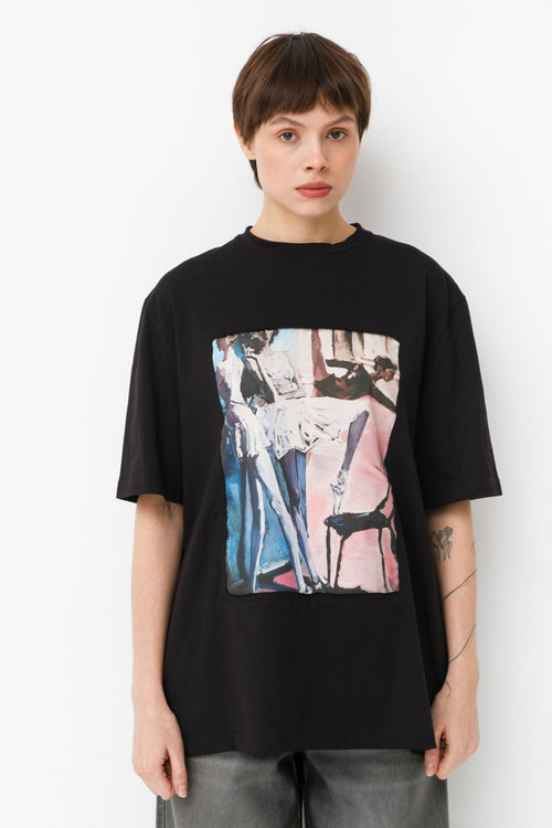 Person wearing a black t-shirt with a colorful ballet design on a white background