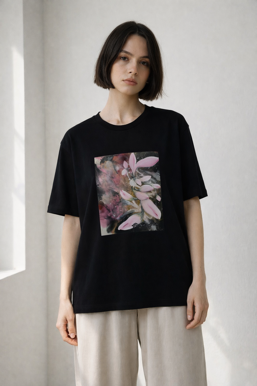 Person wearing a black t-shirt with a floral design on a plain background
