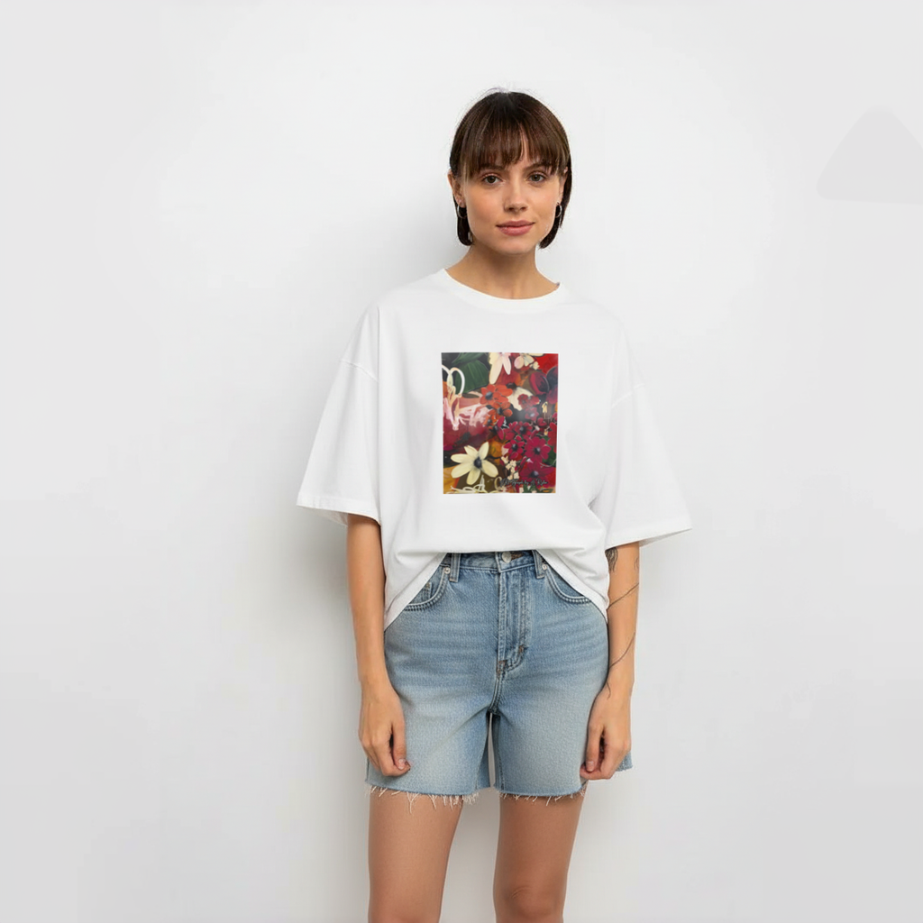 Person wearing a white t-shirt with a colorful floral design and denim shorts on a plain background
