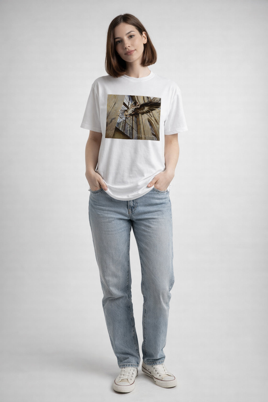 Person wearing a white t-shirt with a artists design and light blue jeans on a plain background