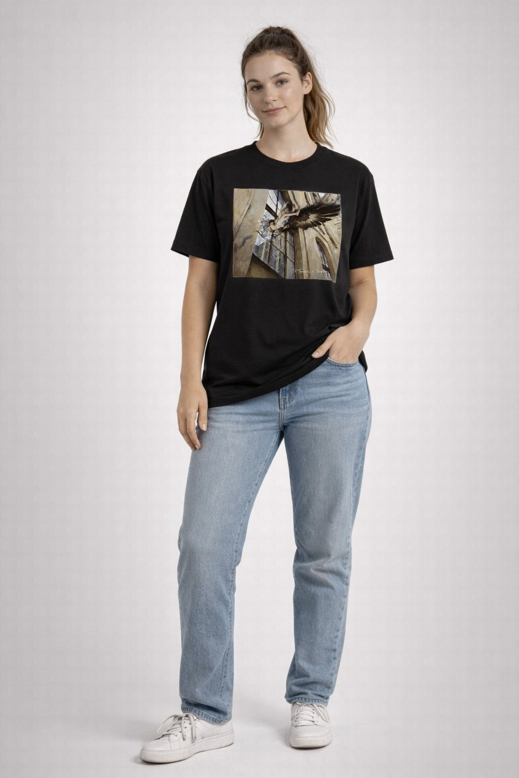 Person wearing a black t-shirt with a graphic design and light blue jeans on a white background