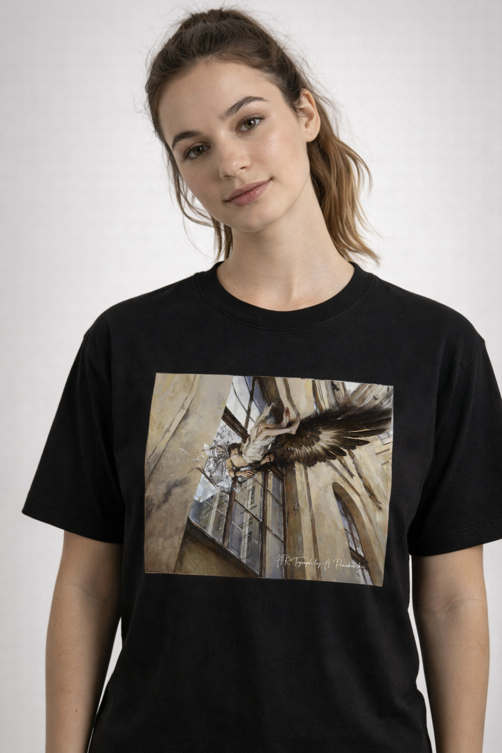 Person wearing a black t-shirt with a printed design on a plain background