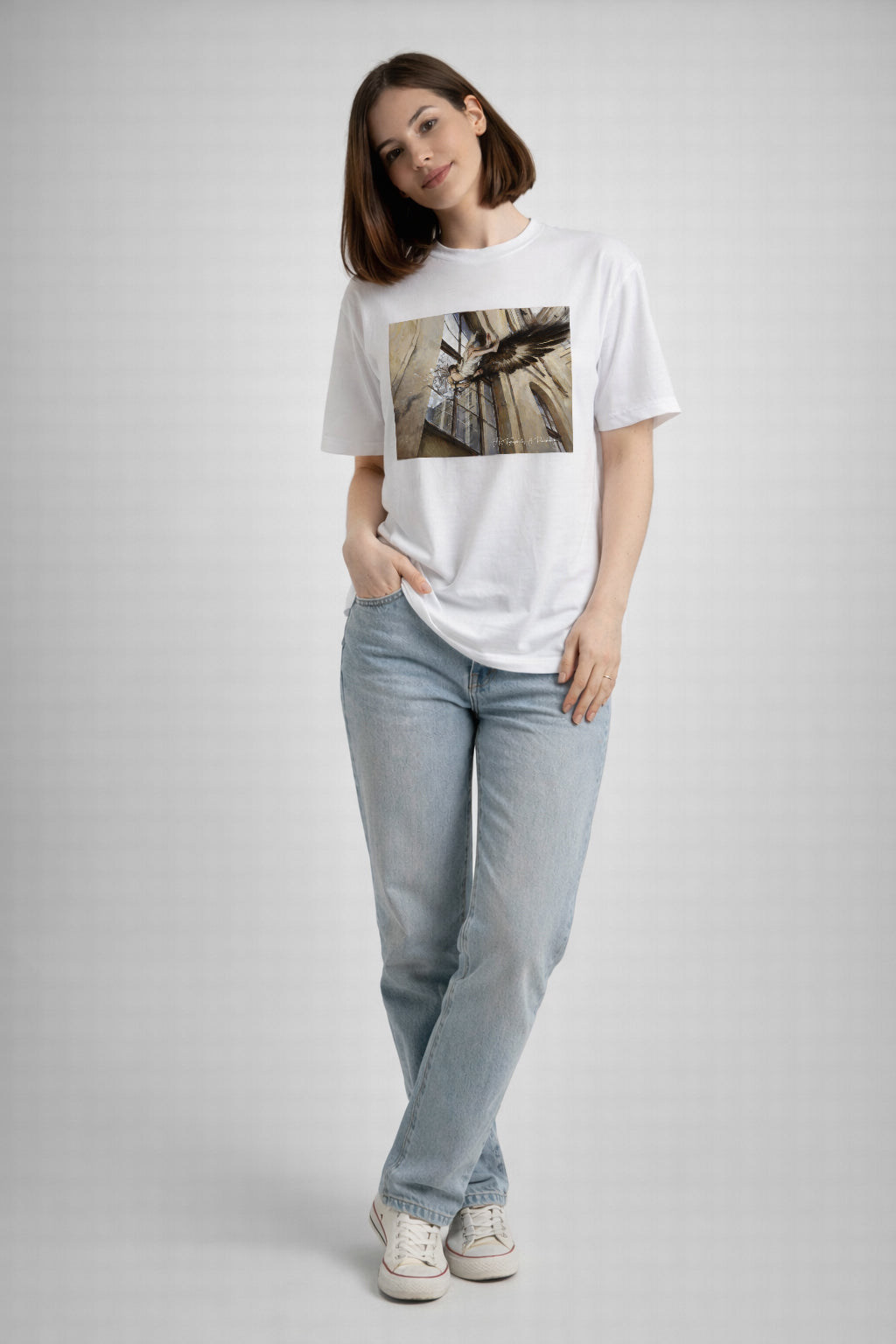 Person wearing a white t-shirt with a graphic design and light blue jeans on a plain background