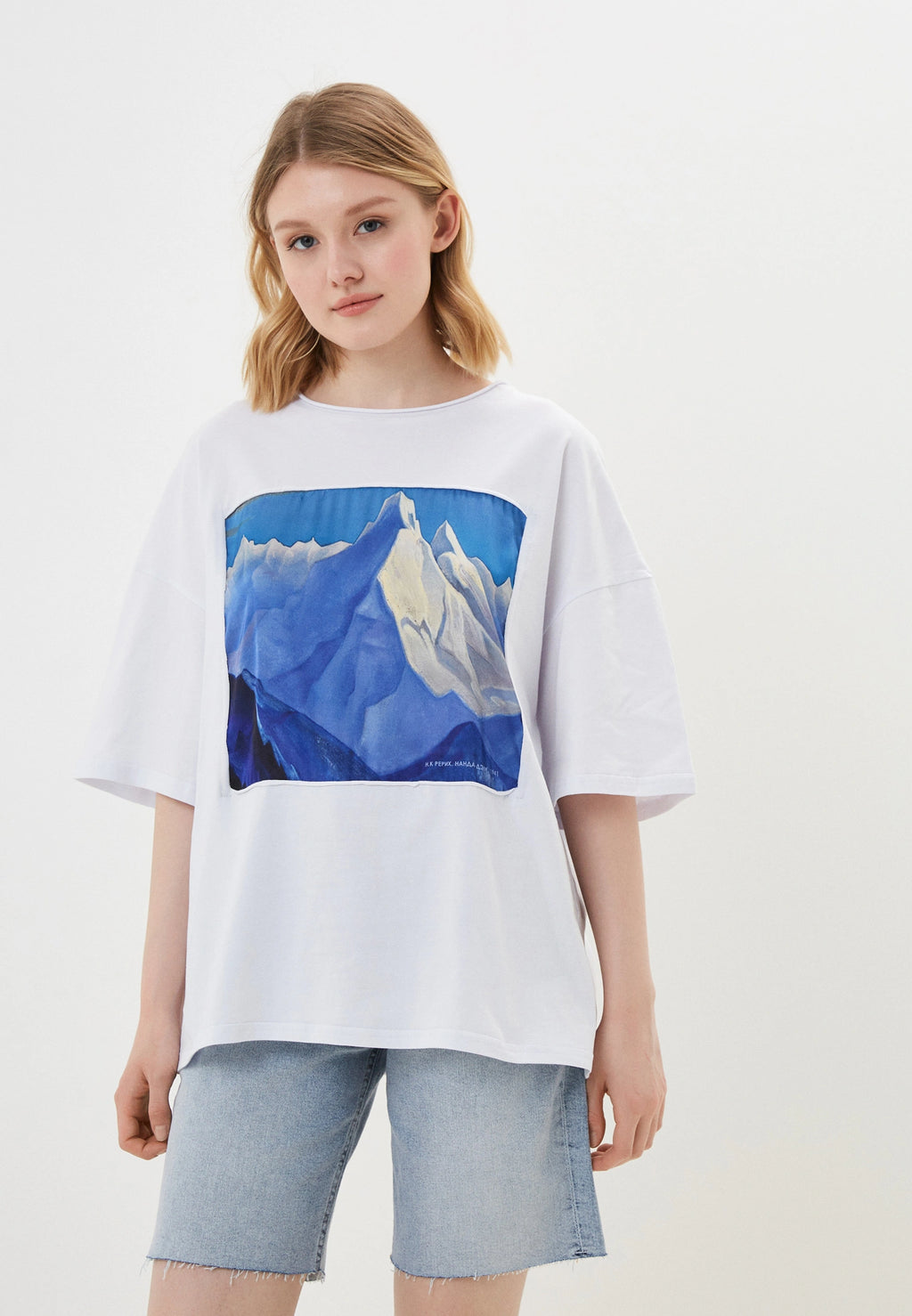 Person wearing a white t-shirt with a graphic design on a plain background