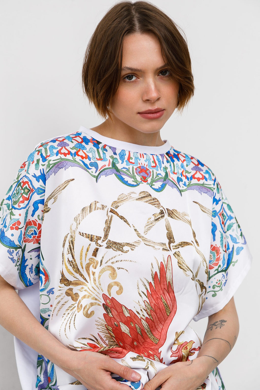 Person wearing a colorful floral and abstract design t-shirt on a white background